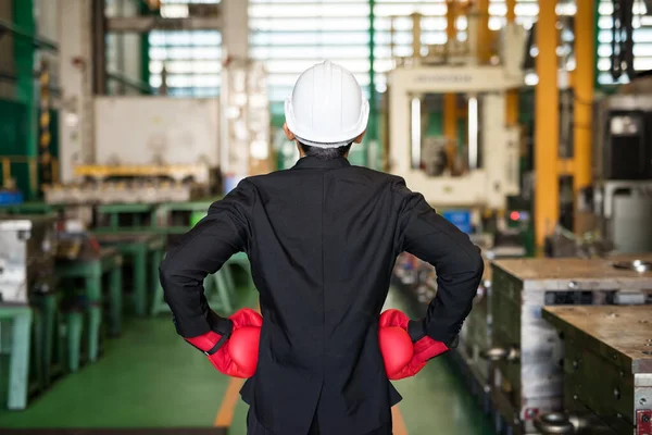 Rear businessman with black suit, red boxing gloves ready for corporate fight during covid-19 or coronavirus pandemic disease. Manufacturing factory. Quarantine, Social distancing, stay work.