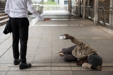 İş adamı hayır diyor ya da şehir zemininde yatan yaşlı, özürlü evsiz adama para vermeyi reddediyor. Yoksulluk ve sosyal mesele kavramı. Şefkatle ver ve paylaş.