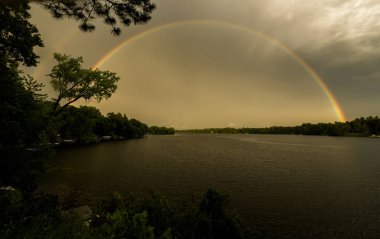 Bir gökkuşağı gölün üzerinde bir köprü oluşturur..