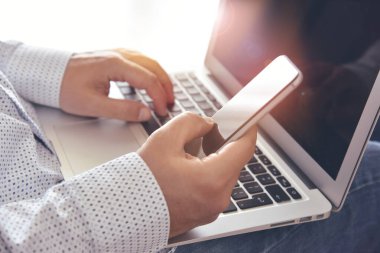 İş iletişimi. Akıllı telefon ve laptop kullanan bir adam. Modern çevrimiçi iletişim, e-ticaret, internet hizmetleri ve uygulamalar kavramı