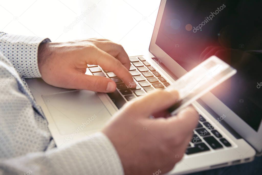 Closeup of man's hands holding credit card and using laptop. Concept for e-commerce, online shopping, e-banking, internet security.