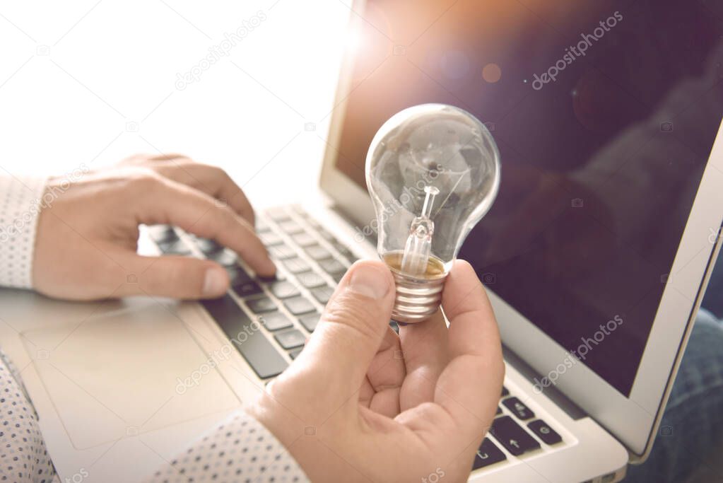 Startup. Man holding electric bulb and using laptop. Concept for background, website banner, poster, presentation templates, social media, advertising and printed materials.