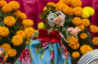 Oaxaca, Oaxaca, Meksika - 1 Kasım 2017: Küçük kafatası geleneksel giysiler ve sarı çiçekler, sunak sunan ölü Meksikalı bir günün bir parçası ile giyinmiş