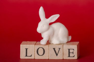 Oyuncak beyaz tavşan kelime aşk kırmızı arka plan ile tahta küpleri ile