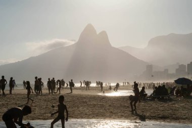 Rio De Janeiro, Brezilya - 14 Ekim 2019: Arkalarında ünlü Dois Irmaos dağıyla birlikte Ipanema Sahili kıyısında oynayan bir grup Brezilyalı