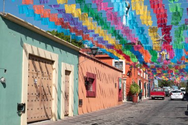OAXACA, OAXACA, MEXICO- DECEMBER 24, 2019: Jalatlaco neighborhood decorated with colorful cut paper, pinatas and stars for Christmas celebration at a sunny day in Oaxaca, Mexico clipart