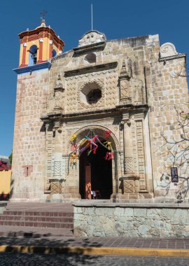 Oaxaca, Oaxaca, Meksika - 24 Aralık 2019: Meksika 'nın Oaxaca kentindeki Jalatlaco mahallesinde güneşli bir günde renkli pinatalarla süslenmiş Templo de San Matias cephesi