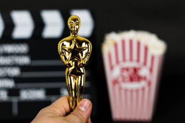 Xalapa, Veracruz, Meksika - 31 Ocak 2020: Arka planda bulanık bir arka plan ve siyah arka planda klasik patlamış mısır kutusu olan plastik Oscar 'ı tutan kadın
