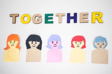 Tahta harflerden ve beyaz arka planda renkli kağıtlardan yapılmış kadınlardan oluşan bir sözcük.