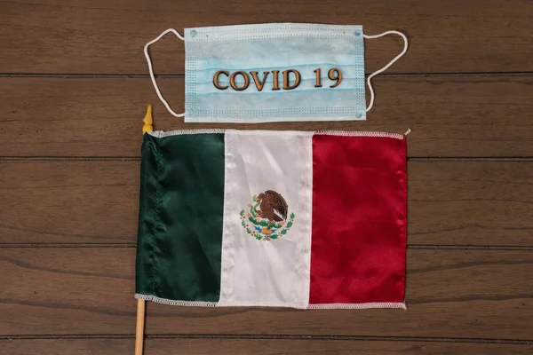 上面写着 Covid 由木制字母和墨西哥国旗做成 背景为木制 — 图库照片