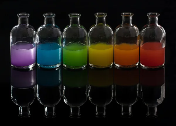 Аптекарь, лабораторные бутылки с цветной жидкостью с отражением — стоковое фото
