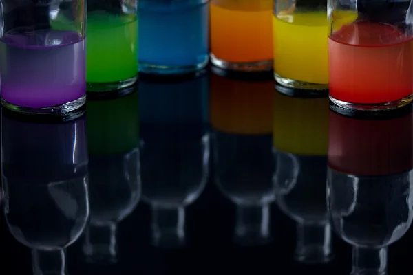 Garrafas boticárias com líquido colorido com reflexão — Fotografia de Stock