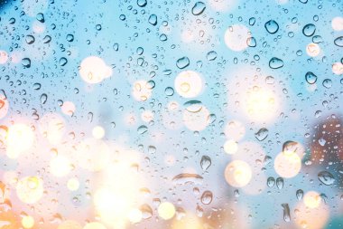 Bokeh ışıkları olan cam pencereye su damlıyor. 