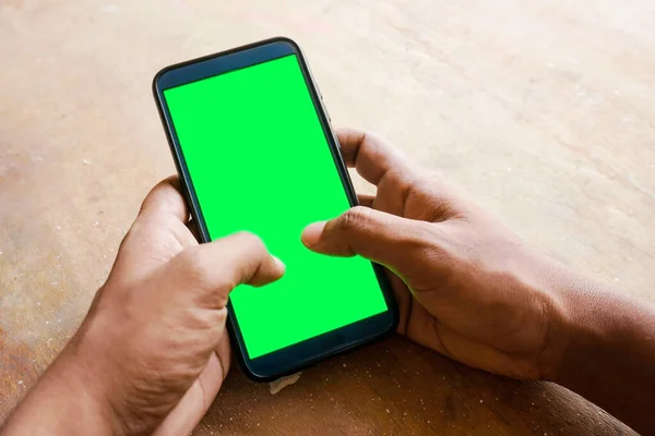 hand holding smart phone with green screen