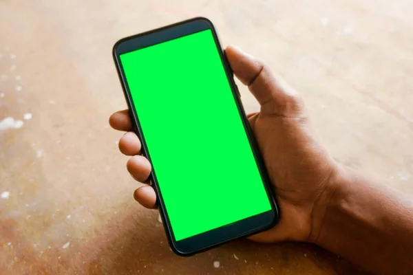 hand holding smart phone with green screen