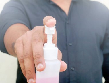 Adam ellerine dezenfektan sürüyor.