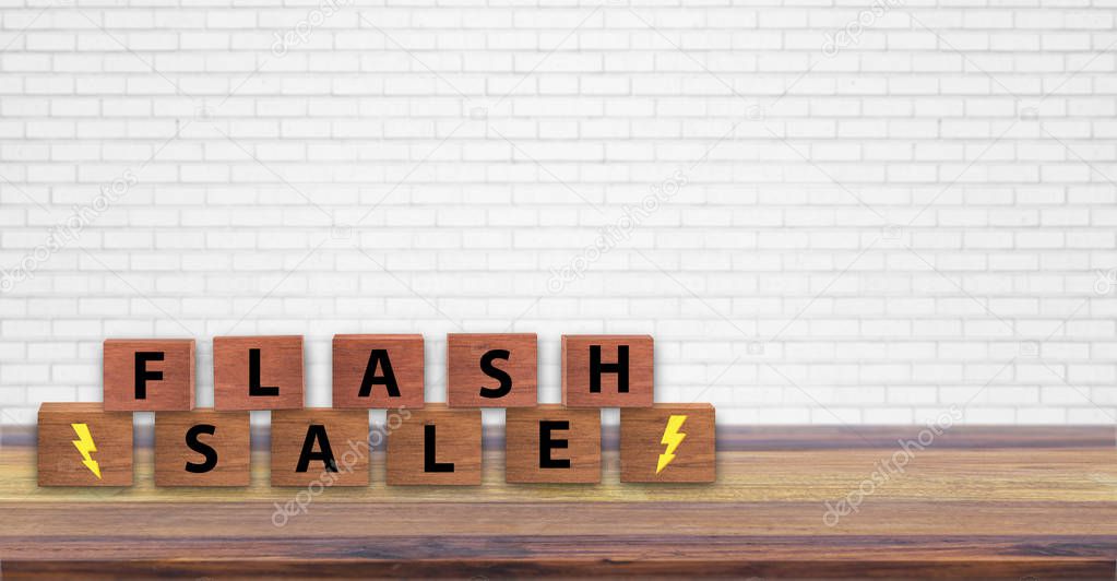 Flash Sale cube alphabet letters on table wooden with white brick wall background. Business concept