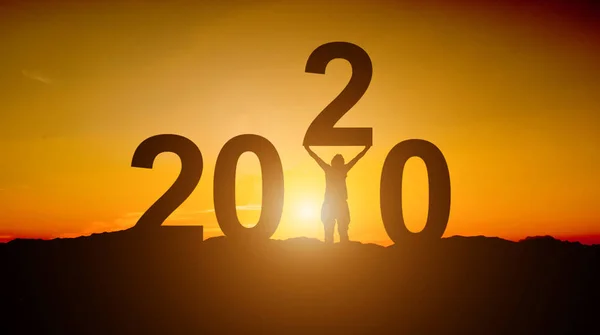 Silhouette des Geschäftsmannes versucht, die Zahl der 2020. glücklich zu heben — Stockfoto