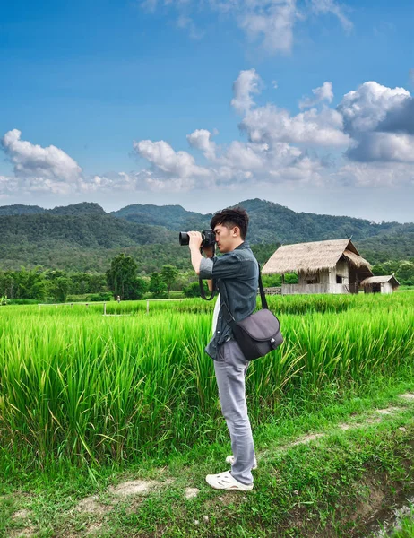 年轻人在稻田用数码相机拍照 旅行和积极生活方式概念 — 图库照片