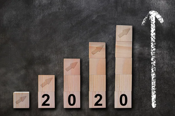 Growing business concept. Wooden cubes graph of success in 2020 year on chalkboard.