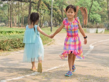 İki küçük kız kardeş yaz mevsiminde el ele tutuşuyorlar.