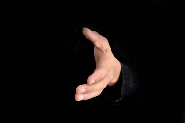 İşadamı el sıkışma ve siyah arkaplan üzerinde işbirliği teklif ediyor. İş anlaşması önerisi kavramı.