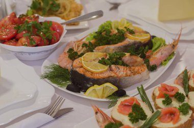 Limonlu maydanoz ve karidesle süslenmiş fırında somon bifteği.