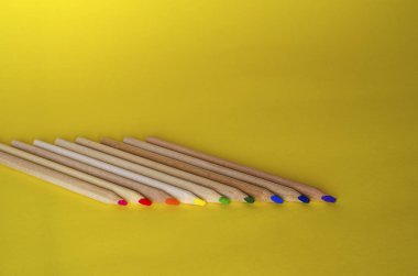 Sarı zemin üzerinde çok renkli kalemler.