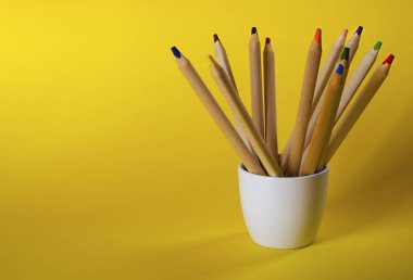 Sarı zemin üzerinde çok renkli kalemler.