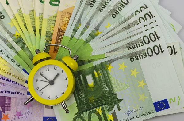 Sarı alarm saati ve farklı değerlerdeki Euro banknotları 2