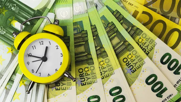 Sarı alarm saati ve farklı değerlerdeki Euro banknotları 5