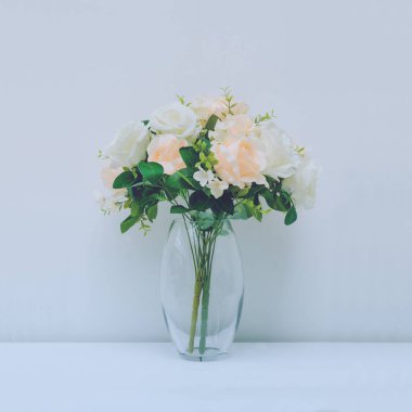 Beautiful artificial roses in arrangement in vase with blue filt
