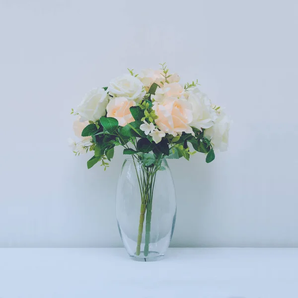 Beautiful artificial roses in arrangement in vase with blue filt 免版税图库照片