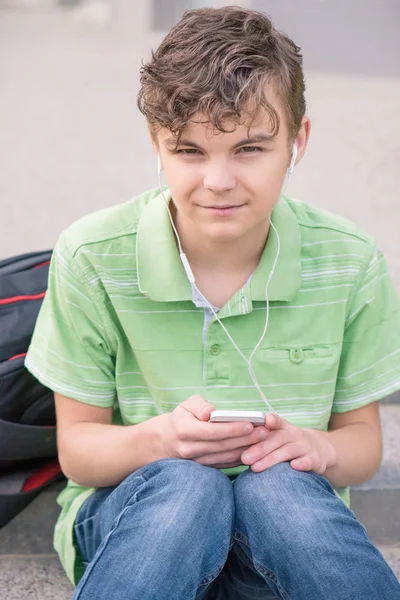 Tiener jongen met hoofdtelefoon en de telefoon — Stockfoto