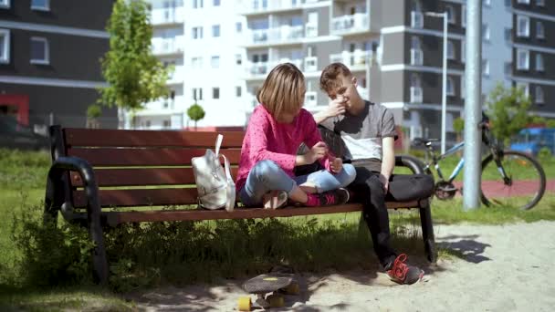 Pojke och flicka sitter på bänken — Stockvideo