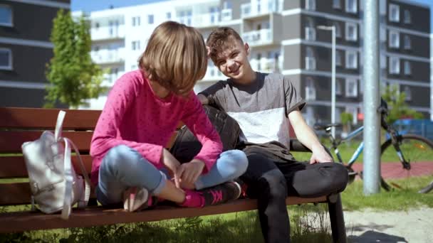 Niño y niña sentados en el banco — Vídeos de Stock