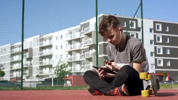 Dospívající chlapec se sluchátky a tablet — Stock video