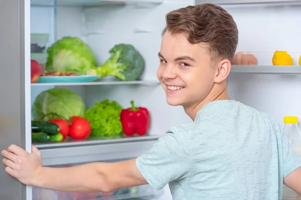 冷蔵庫の近くの食べ物を持つ少年 — ストック写真