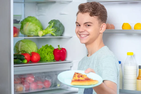 Хлопчик з їжею біля холодильника — стокове фото