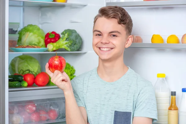 Мальчик с едой возле холодильника — стоковое фото