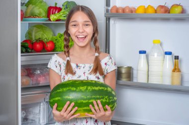 Buzdolabının yanında yemeği olan kız.