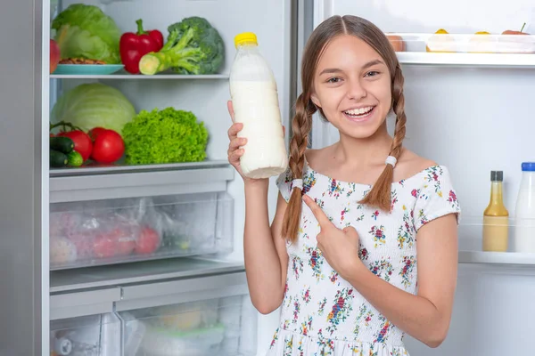 Fille avec de la nourriture près du réfrigérateur — Photo