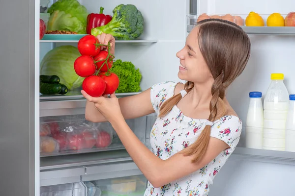Flicka med mat nära kylskåp — Stockfoto
