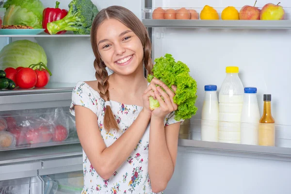 Flicka med mat nära kylskåp — Stockfoto