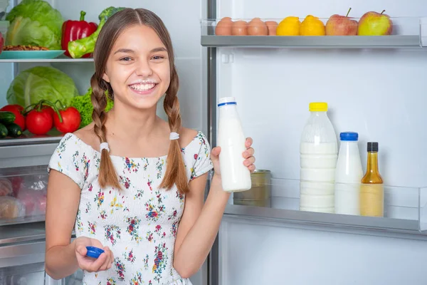 Menina com comida perto da geladeira — Fotografia de Stock