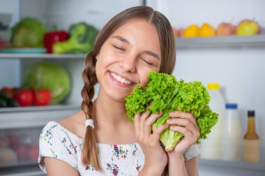 Buzdolabının yanında yemeği olan kız.