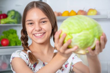 Buzdolabının yanında yemeği olan kız.