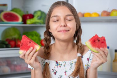 Buzdolabının yanında yemeği olan kız.