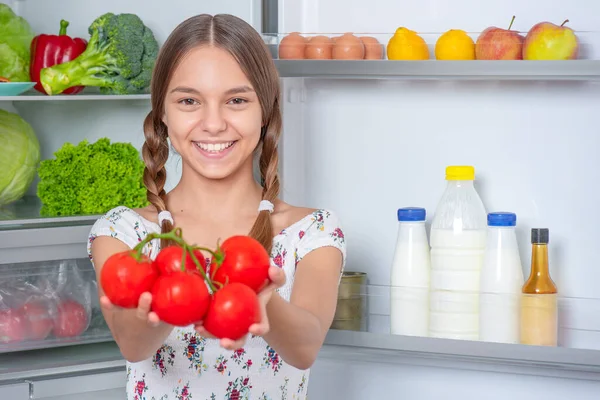 Menina com comida perto da geladeira — Fotografia de Stock