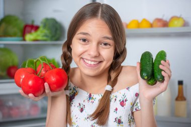 Buzdolabının yanında yemeği olan kız.
